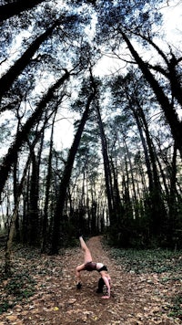 a woman doing a handstand in the woods