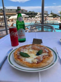 a pizza on a plate next to a bottle of coca cola
