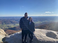 a man and woman standing on top of a mountain