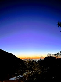 a sunset over a hill with a mountain in the background