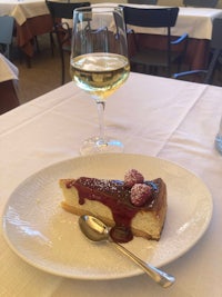a piece of cheesecake on a plate next to a glass of wine