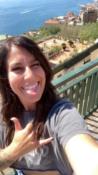 a woman is taking a selfie on a balcony overlooking the sea