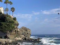 a man is flying a kite over a rocky beach