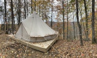 a tent sits on top of a wooden deck in the woods