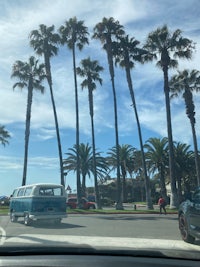 a car driving down a street with palm trees in the background