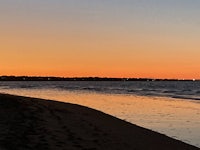 a person is walking on a beach at sunset