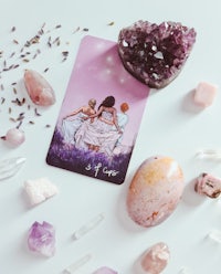 a tarot card, crystals, and stones on a white table