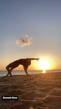 a woman doing yoga on the beach at sunset