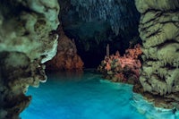a cave with blue water and rocks in it